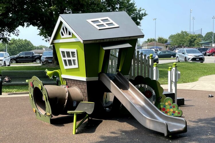 green cottage-shaped structure with slide and tunnel