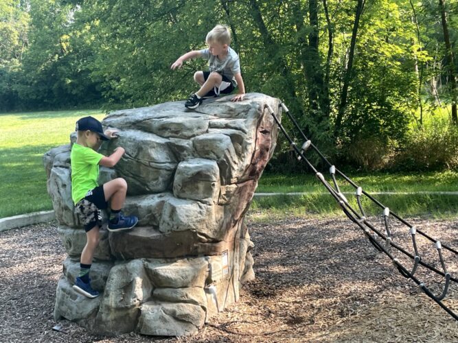 two children climbing an adventure scapes rock