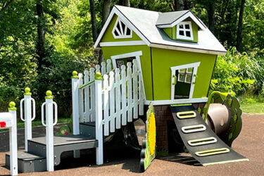 green playhouse with climbing wall entrance and stairs