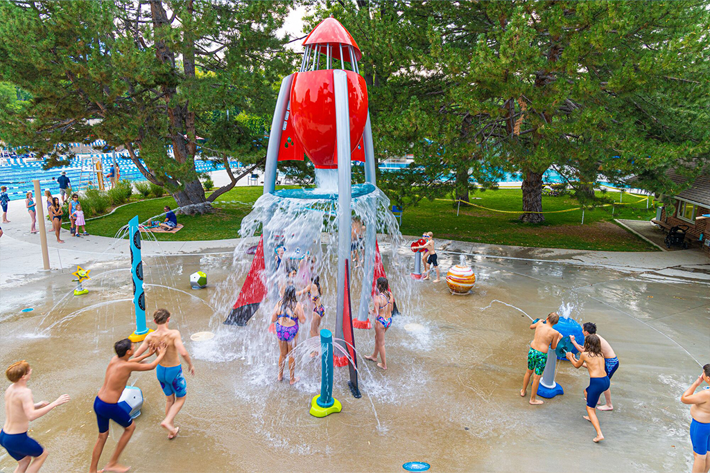 Kids playing at rocket shaped water feature at splash pad