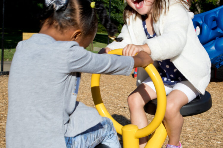 close up of two kids laughing on the rocking toy