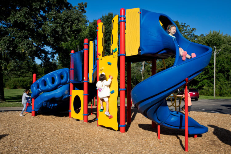 side view of playground climbing wall to tower with two slides