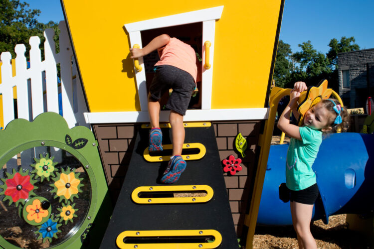 young boy climbing into playhouse from climbing wall