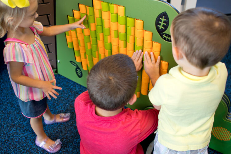 3 kids playing at rotating wall that can create patterns or images
