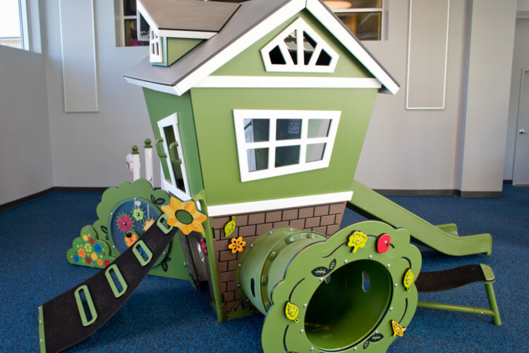green playhouse with climbing tube below it