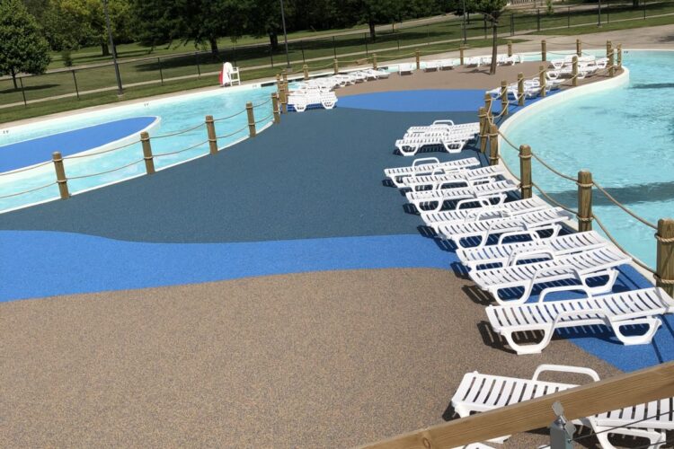 lawn chairs lined up along colored surface surrounding pool