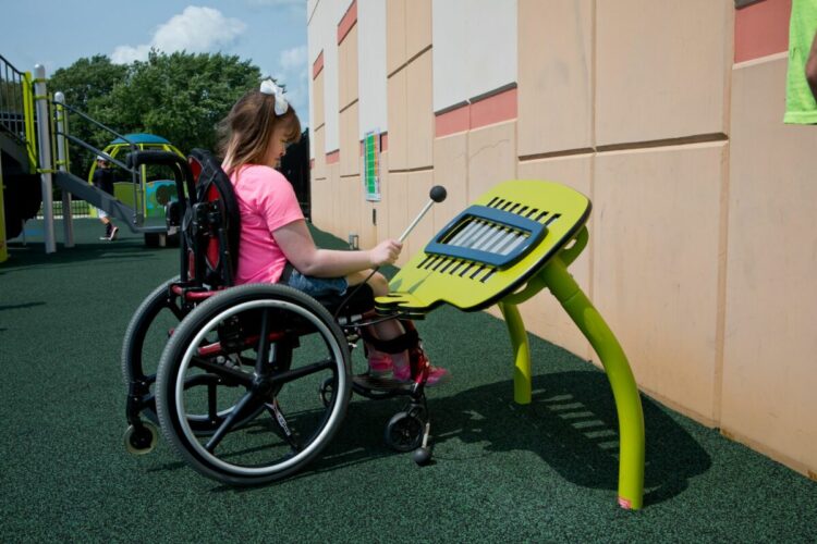 girl in wheelchair playing with accessible playground equipment