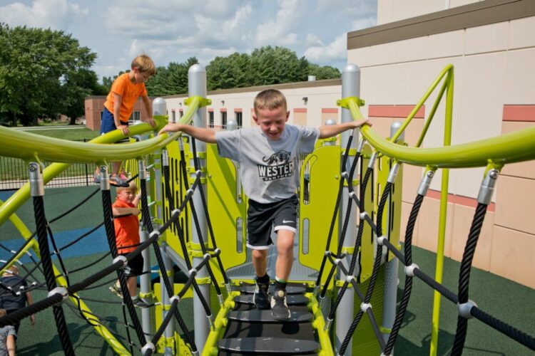 young boy running across rope bridge