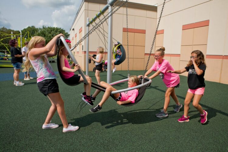 girls pushing other girls in a sling swing