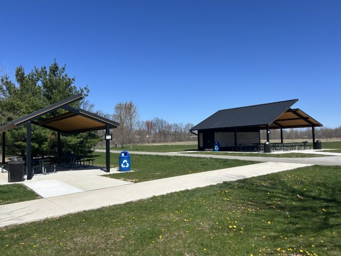 Two 2-tier metal shelter with tongue and groove shelter with trash receptacle and picnic tables
