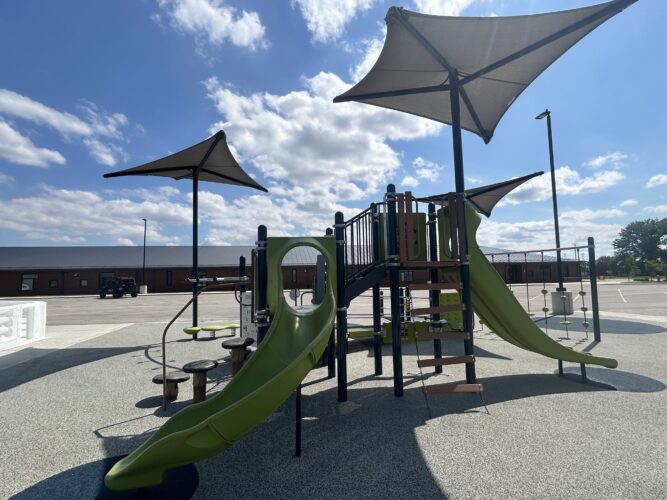 Green and brown play structure with one winding slide and a double slide