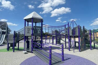 Wheelchair ramp to purple and silver play structure with a bridge, fireman pole, slide, and climber