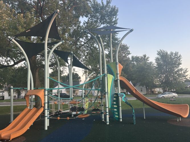 orange, blue, lime green, and teal play structure for kids ages 5-12 with 3 slides, climbing cables, and integrated shade