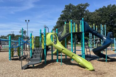 play structure for 5-12 year olds with a green slide and blue curly slide