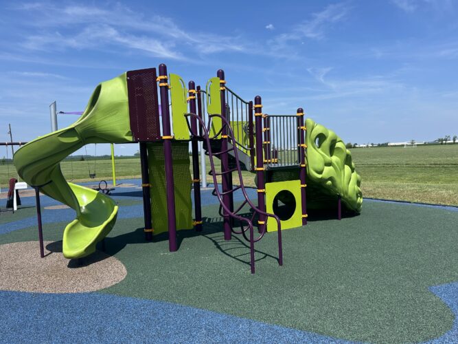 green, purple, and orange play structure with a climber and curly slide for kids ages 5-12