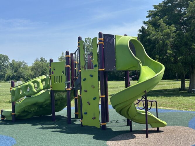 purple, lime green, and orange play structure with curly slide and wall climber