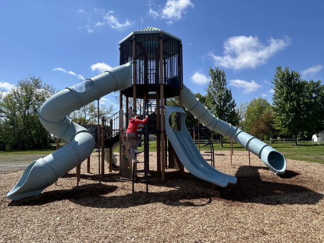2 story play structure with 2 curvy tunnel slides and a double slide
