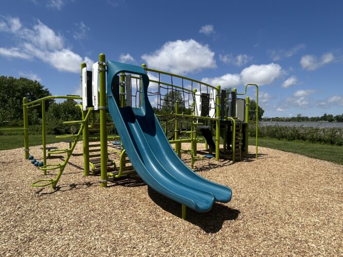 blue and green playground with double slide and rope bridge