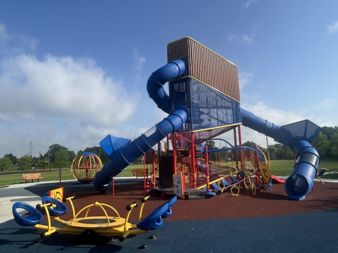 large red, blue, and yellow play structure with a curly slide, 4-person see-saw