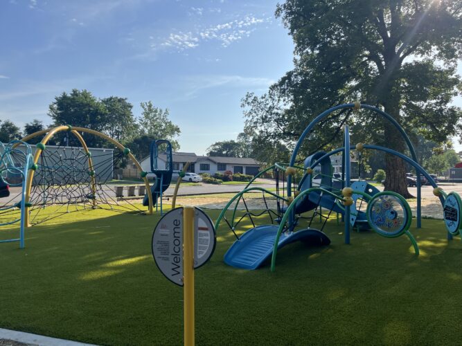 playground with a welcome sign and blue bridge