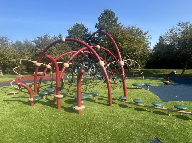 red and brown play structure with green turf