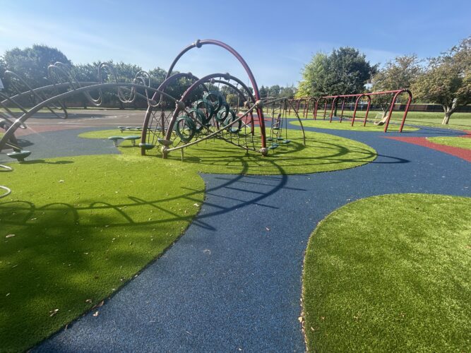 play structure for kids aged 5-12 with green turf and blue rubber surfacing