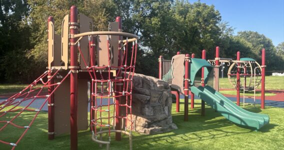 red, brown, and green play structure with climbing nets, climbing rock, and slide