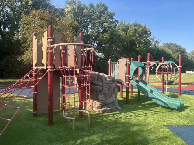 red, brown, and green play structure with climbing nets, climbing rock, and slide