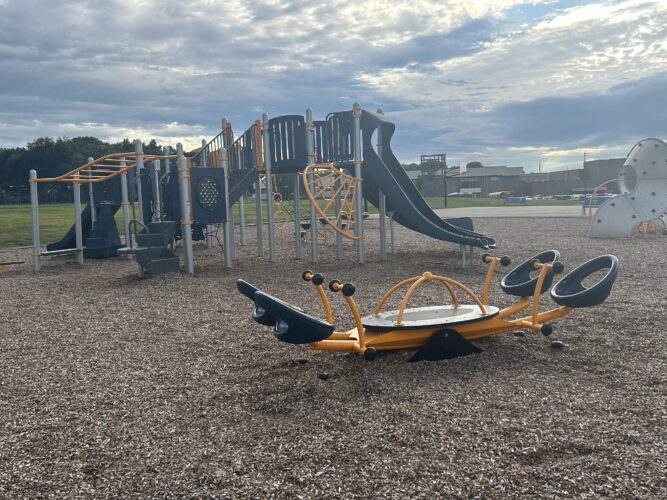 blue and orange see saw with a play structures for kids ages 5-12