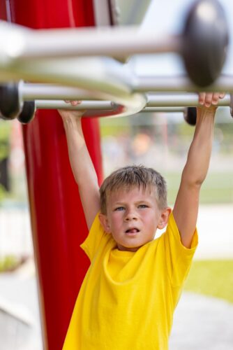 little boy playing on the monkey bars